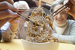 People sharing noodles, close-up