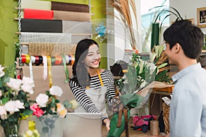 People, shopping, sale, floristry and consumerism concept - happy smiling florist woman making bouquet for and man or customer at