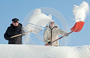 People shovelling snow on a roof
