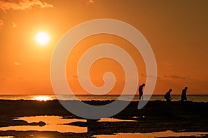 People silhouetted against a tropical sunset