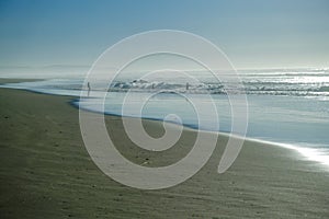 People silhouetted on the beach fishing and playing as the surf come in