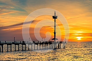 People silhouettes on Brighton Jetty at sunset