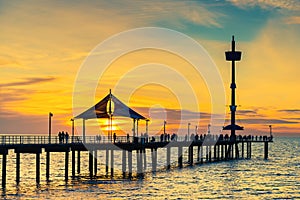 People silhouettes on Brighton Jetty at sunset
