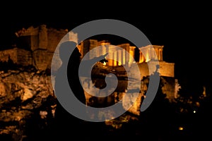 People silhouettes in the foreground, with Acropolis night view at the background