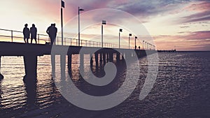 People silhouettes on Frankston pier at sunset.