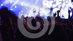 People silhouettes jump waving hands, taking photos or recording videos of live music concert with smartphones at open