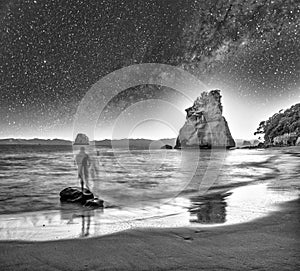 People silhouettes looking at Cathedral Cove marine reserve, Coromandel Peninsula,  New Zealand on a starry night