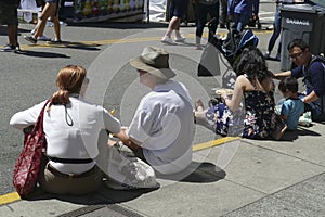 People sit on the curb to eat fast food