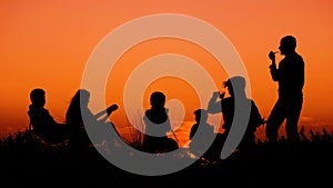 People sitting on the beach with campfire at sunset