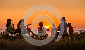 People sitting on the beach with campfire at sunset