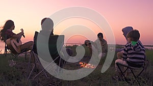 People sitting on the beach with campfire at sunset