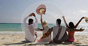 People sitting on beach talking happy raised hands back rear view, men and women communication tourists group on summer