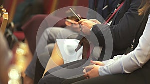 People sitting at business conference, man with smartphone in hands