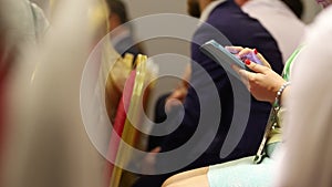 People sitting at business conference, man with smartphone in hands