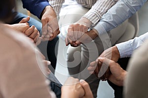 People sitting in circle holding hands at group therapy session