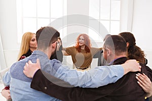 People sitting in circle, hugging each other