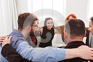 People sitting in circle, hugging each other