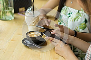 People are sitting on the phone and drinking coffee on a wooden table in a restaurant.