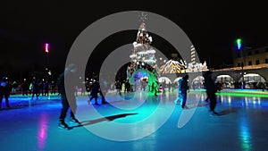 People skate on an ice skating rink with a Christmas tree in the center