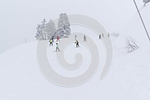 People skiing down from slope during snowfall photo