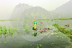 People with small boat on Van Long pond, Ninh Binh province, Vietnam