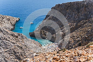 people spending summer vacation on Seitan Limania beach surrounded by rocky mountains, Crete