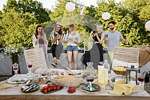People spending time together, sitting separately in smart phones at party outdoors