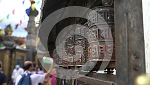 People spinning religious prayer wheels with written mantra Om Mani Padme Hum. Kathmandu, Nepal.