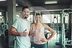 People sport couple concept in fitness gym are giving thumbs up for symbol good health., Portrait of couple in sportswear are