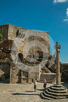 People on square with pillory in front of stone castle