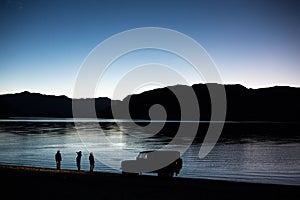 People standing by the lake with a truck Landrover