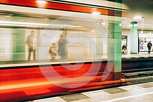 People standing at platform and blurred train coming to the subway station in city Berlin at Germany