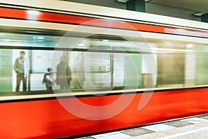 People standing at platform and blurred train coming to the subway station in city Berlin at Germany