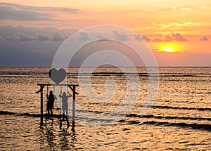 People standing on swing with beautiful sunset, Gili Trawagan