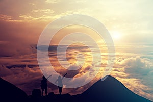 People standing on the top of the mountain above the clouds.