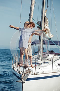 People standing on yacht railings close to each other like Titanic pose.