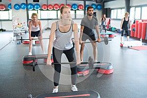 people in step exercise class holding weights