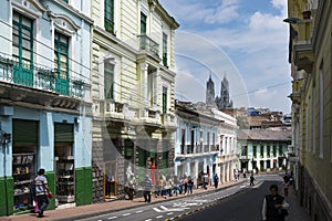 People in a street in the historic center of the city of Quito, in Ecuador, with the Basilica of the National Vow on the backgroun