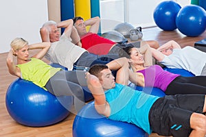 People stretching on exercise balls in fitness club