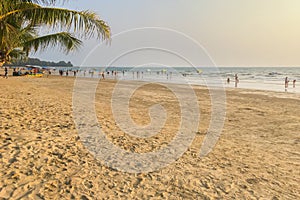 People stroll the beach, sea and sand in the evening during the summer holidays