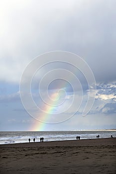 People stroll on north sea beach in holland with cloudy sky and