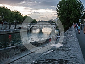 People stroll by the Seine on a summer evening in Paris