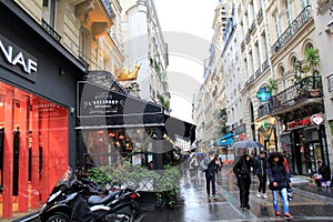 People strolling through the rain, holding umbrellas, near famous restaurant, L'Escargot, Paris, France, 2016