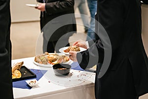 People in suits serve themselves at the buffet and eat delicious food at a business event