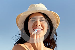 smiling woman in bikini with lip balm on beach photo