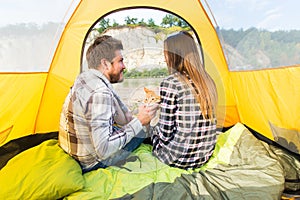 People, summer tourism and nature concept - young couple resting in camping tent, view from inside