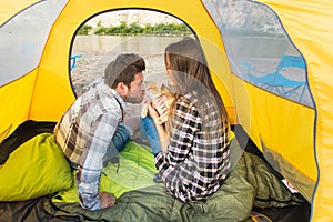 People, summer tourism and nature concept - young couple resting in camping tent, view from inside