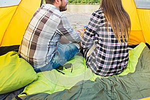 People, summer tourism and nature concept - young couple resting in camping tent, view from inside