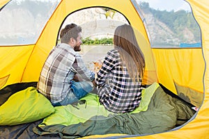 People, summer tourism and nature concept - young couple resting in camping tent, view from inside