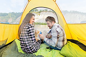 People, summer tourism and nature concept - young couple resting in camping tent, view from inside